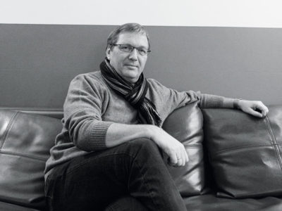 Ein Mann mit Brille sitzt auf einem Ledersofa.