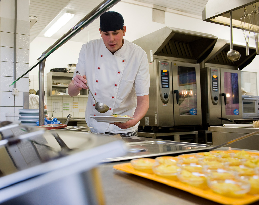 Ein junger Mann füllt etwas auf einen Teller.