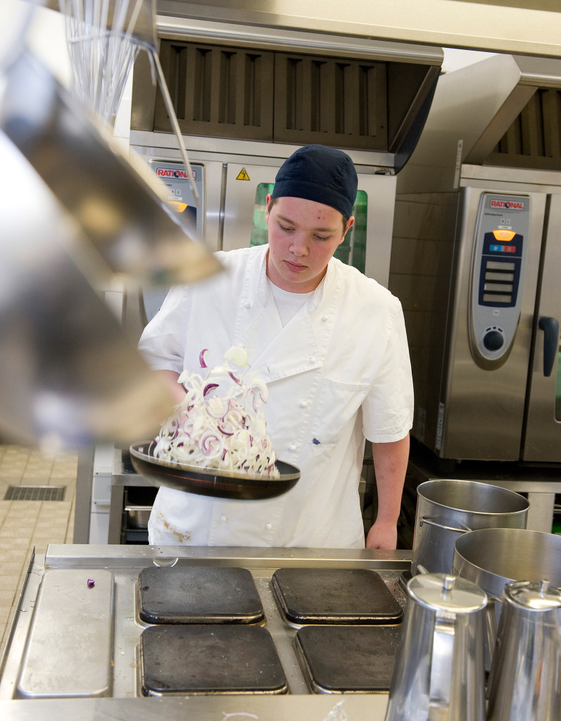 EIn junger Mann hält eine Pfanne in der Hand.