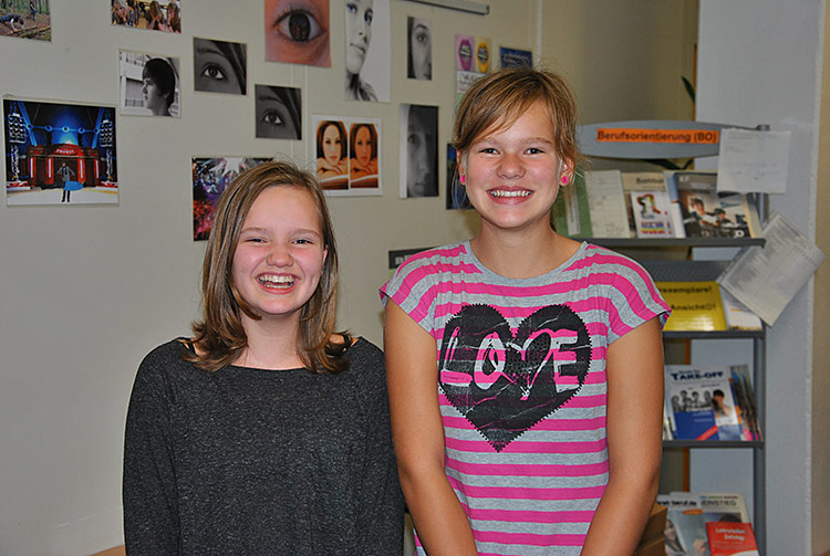 Zwei Schülerinnen lächeln in die Kamera.