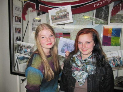 Zwei Schülerinnen stehen vor einer Wand mit Fotos.
