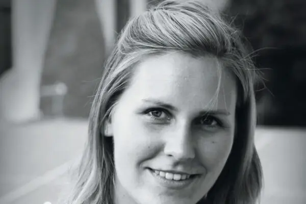 Eine blonde junge Frau lächelt in die Kamera.
