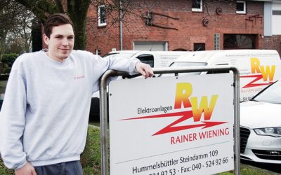 Ein junger Mann im grauen Pulli lehnt sich auf ein Schild.