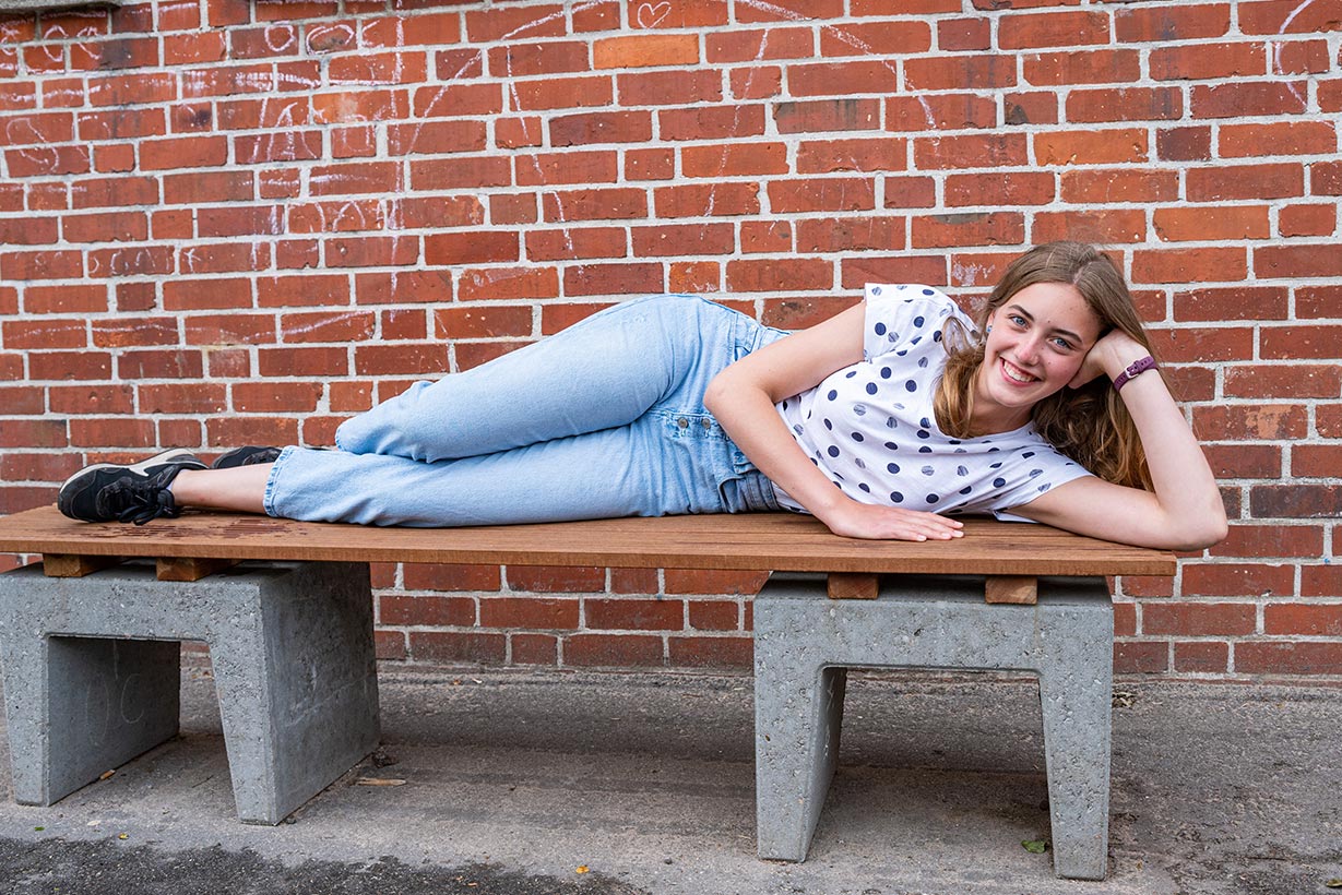Ein Mädchen liegt auf einer Bank.