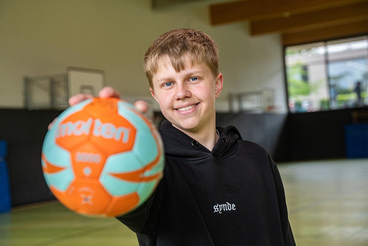 Ein Junge hält einen Handball in die Kamera.