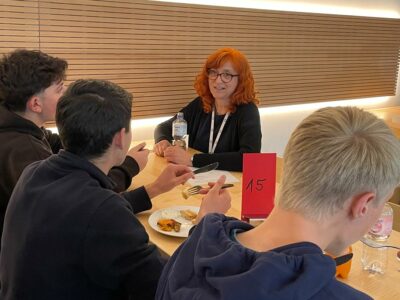 Eine rothaarige Frau spricht mit einer Gruppe Schüler