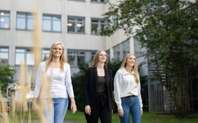 Drei junge Frauen gehen einen Weg entlang.