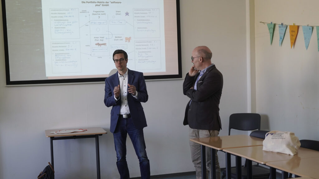 Prof. Dr. Lasse Tausch-Nebel, Programmverantwortlicher des Studiengangs Betriebswirtschaft und Prof. Dr. Bosco Lehr, Dekan des Fachbereichs Wirtschaft an der Hochschule Flensburg, erläutern an der Beruflichen Schule Husum die die Vorteiles der Kooperation
